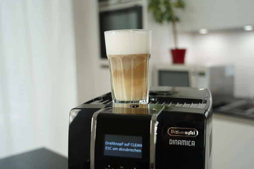 Vaso de latte macchiato recién hecho sobre la DeLonghi Dinamica