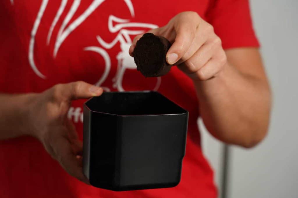 Arne saca una pastilla de café del depósito para posos de café