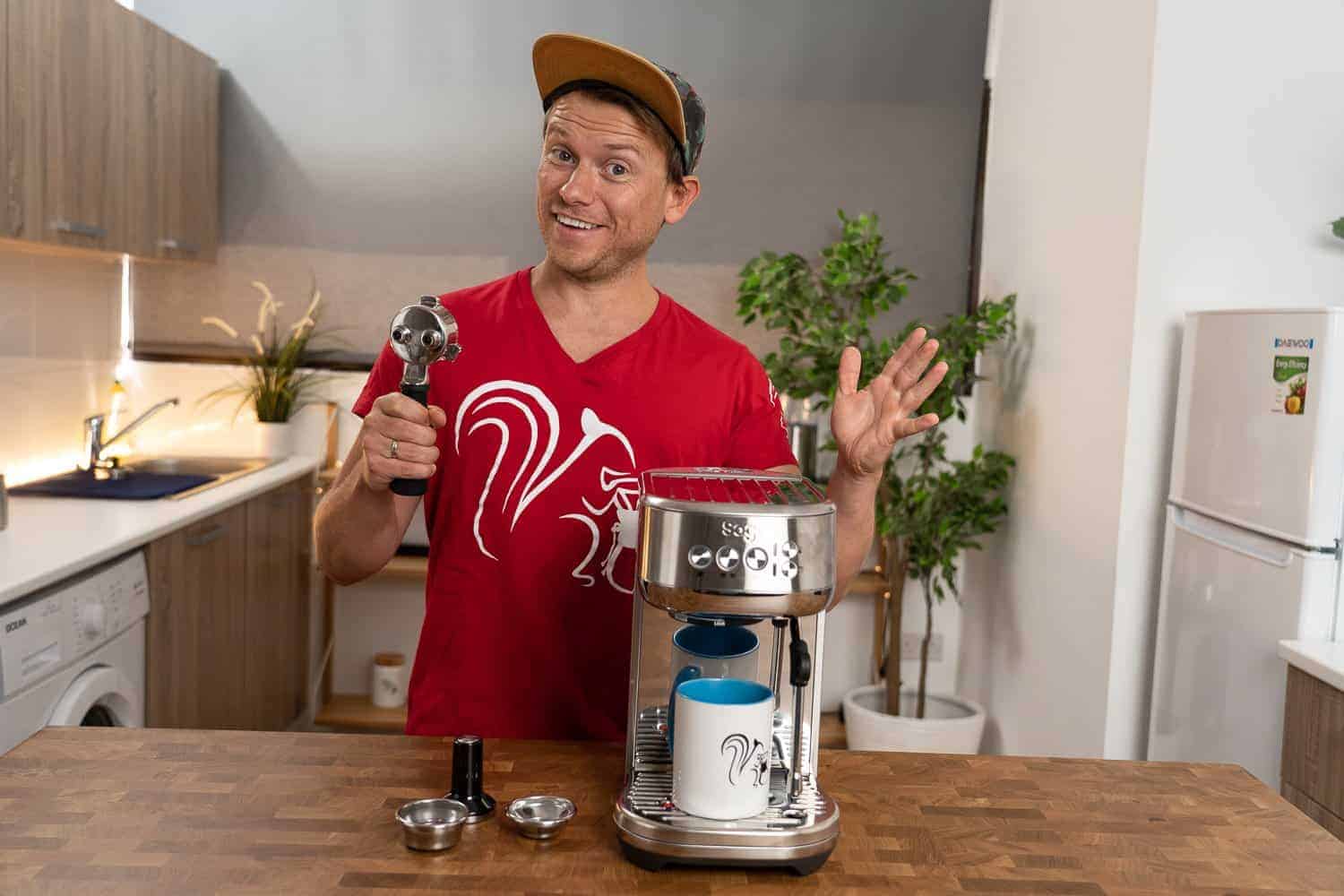 Arne posa feliz con la cafetera expreso Sage The Bambino Plus con el portafiltro en la mano