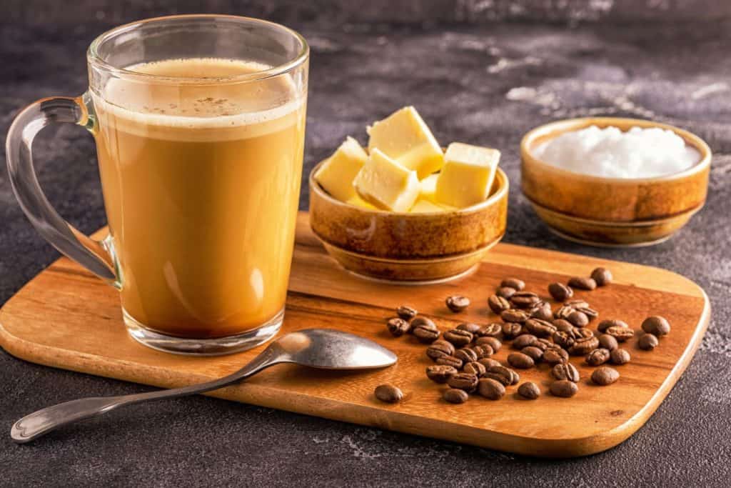 Taza de bulletproof coffee junto a todos los ingredientes