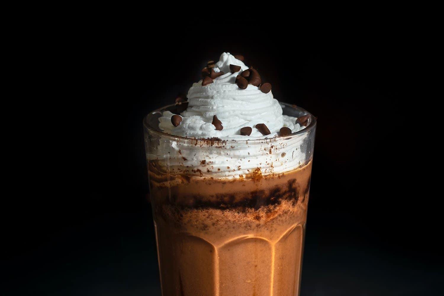 Two ice cold coffee drinks in drinking glasses near black framed