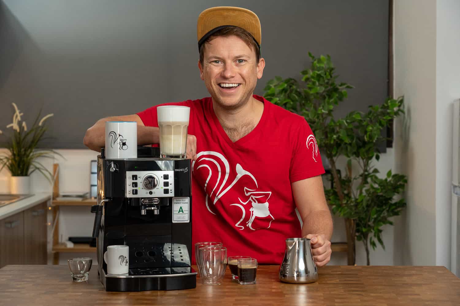 Arne posa sonriente con la cafetera superautomática DeLonghi Magnifica ECAM 22.110.B y algunas bebidas preparadas