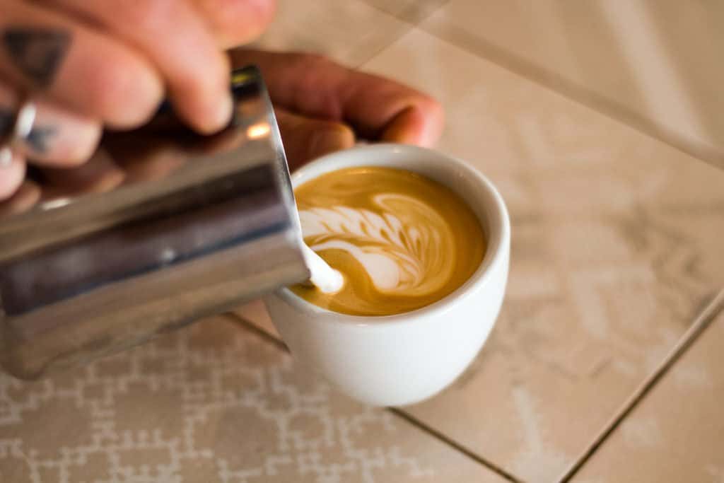 Haciendo latte art con un capuchino en la prueba de granos de expreso de Flying Roasters
