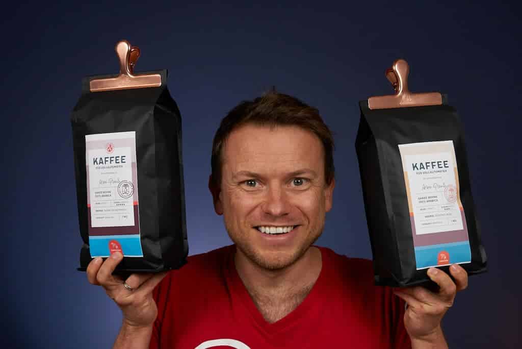 Arne posa sonriente con un paquete de café de Coffeeness en cada mano, en una la variedad clásica y en otra la intensa