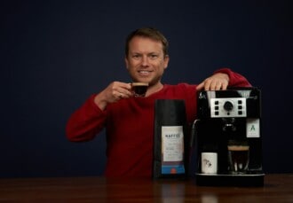 Arne posa sonriente con una expreso recién hecho con la DeLonghi Magnifica y su café de Coffeeness