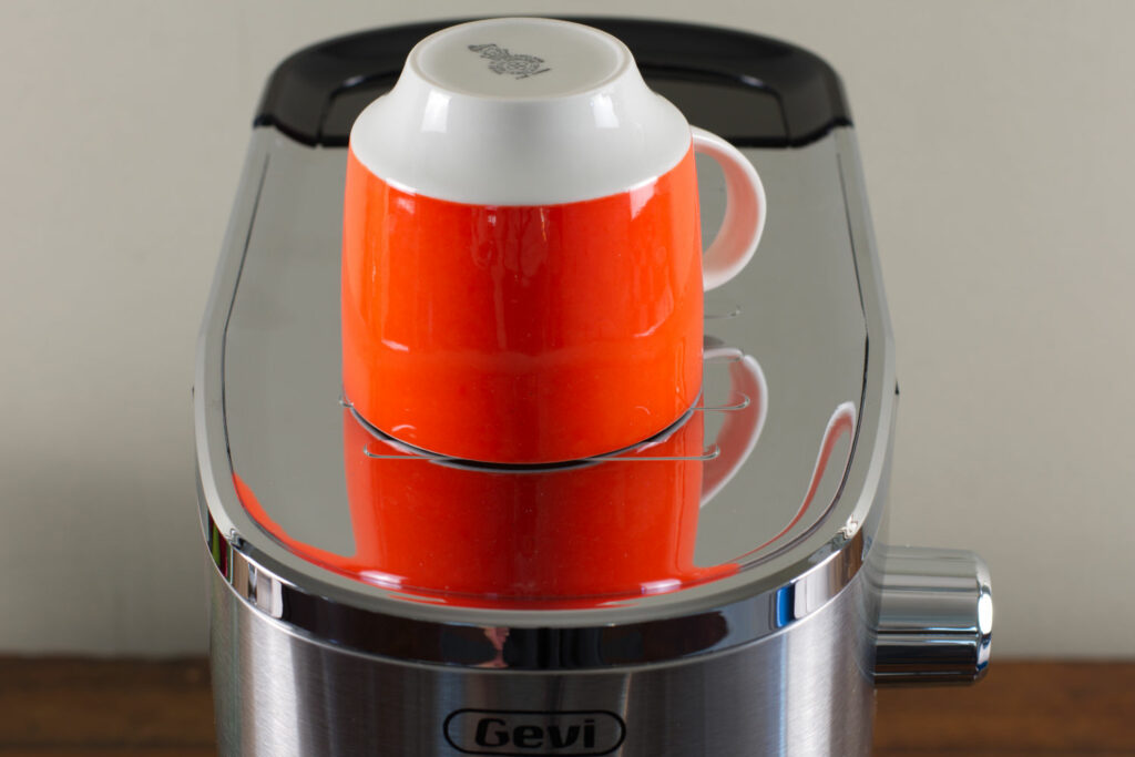 A red cup sitting on the Gevi espresso maker's cup warmer.