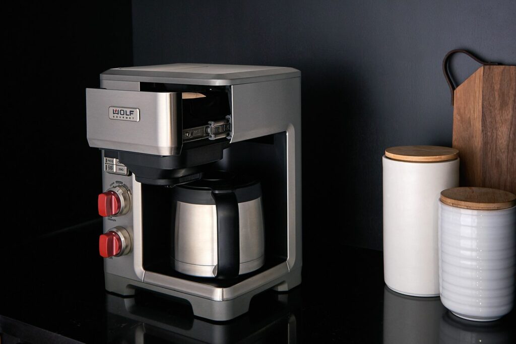 The Wolf Gourmet coffee maker with its front loading brew basket open