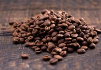 Primer plano de un montón de granos de café sobre una mesa de madera
